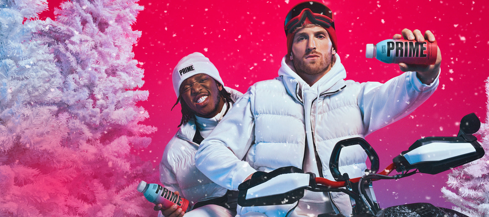 Logan Paul and KSI posing over a red background on a snowmobile with white puffer coats on, holding the new Prime Hydration drink flavor Cherry Freeze